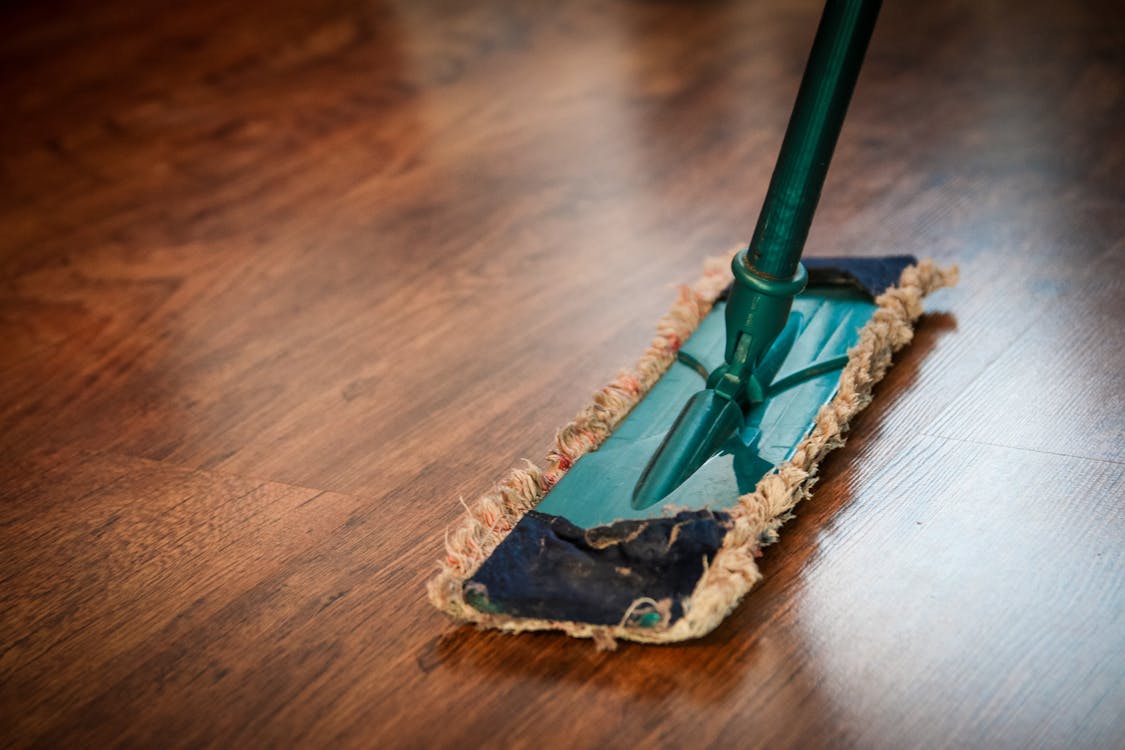 A green mop on a wooden floor.